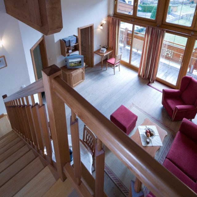 Helle Wohnlandschaft mit Treppe und großen Fenstern.